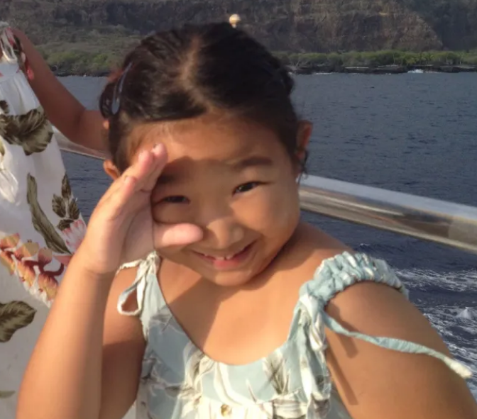 Young Sujin making a circle around her eye with her fingers